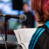 Young person with pink hair reading poem with microphone